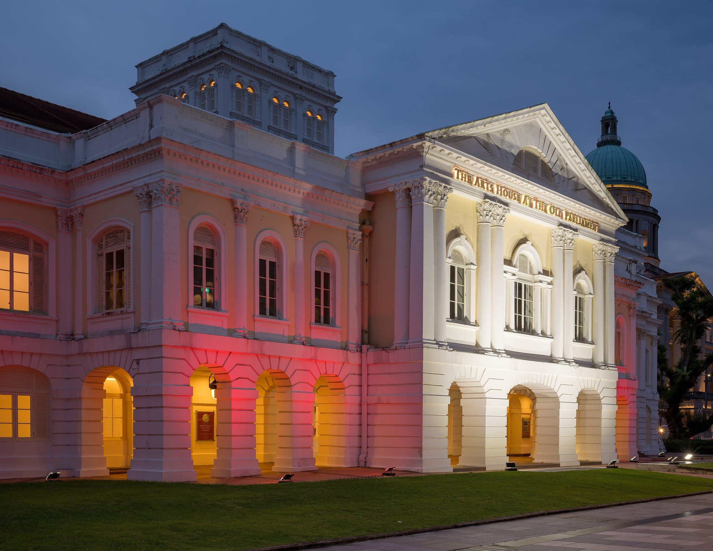 The Arts House di gedung Parlemen Lama di kawasan sipil Singapura, diterangi lampu saat langit senja membiru