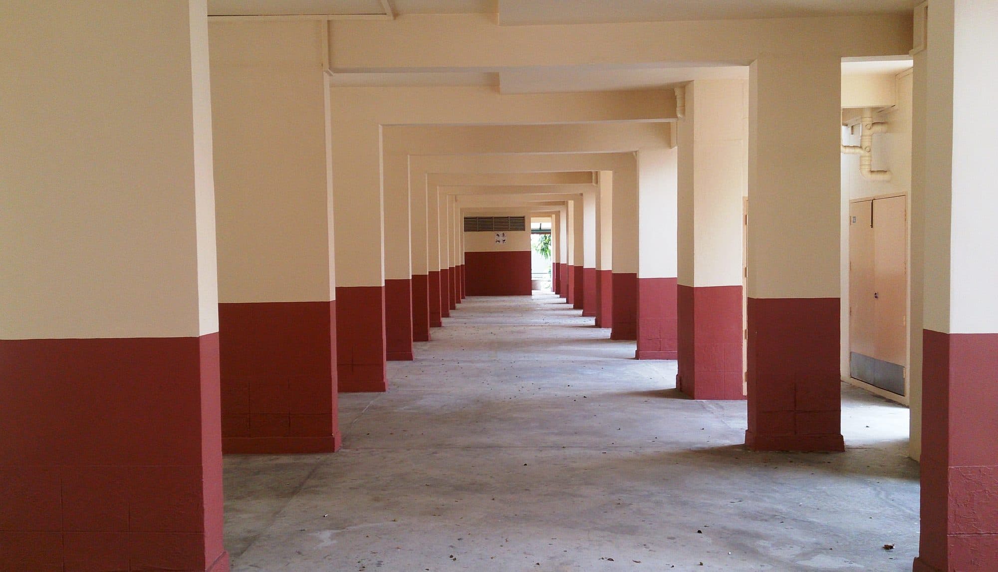Void deck terbuka di bawah blok flat HDB di Singapura, dengan deretan tiang yang memanjang ke kejauhan